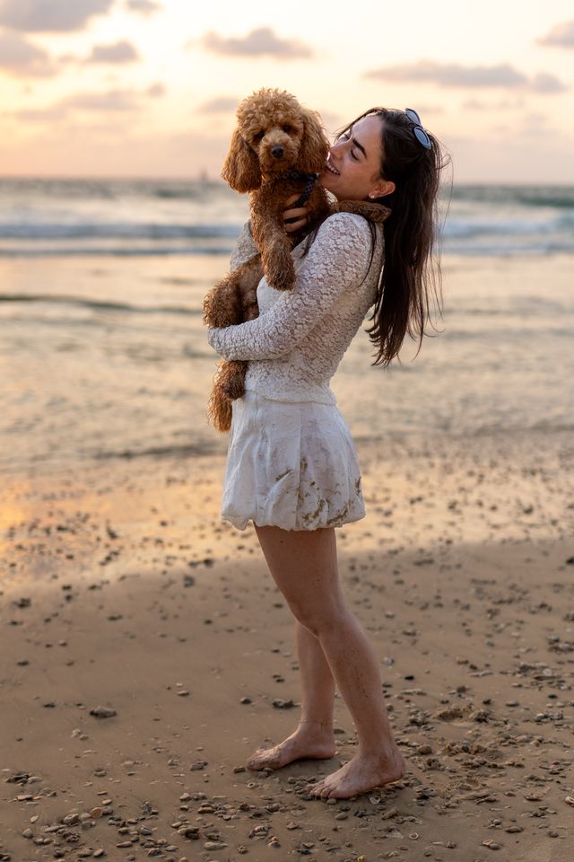 אישה מחבקת כלבלב על החוף באור רך