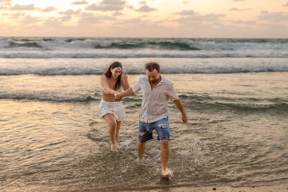 זוג רץ יד ביד במים הרדודים